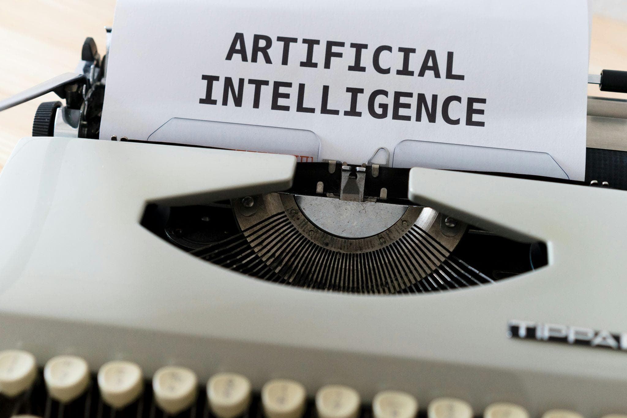 A typewriter with a sheet of paper reading “Artificial Intelligence”