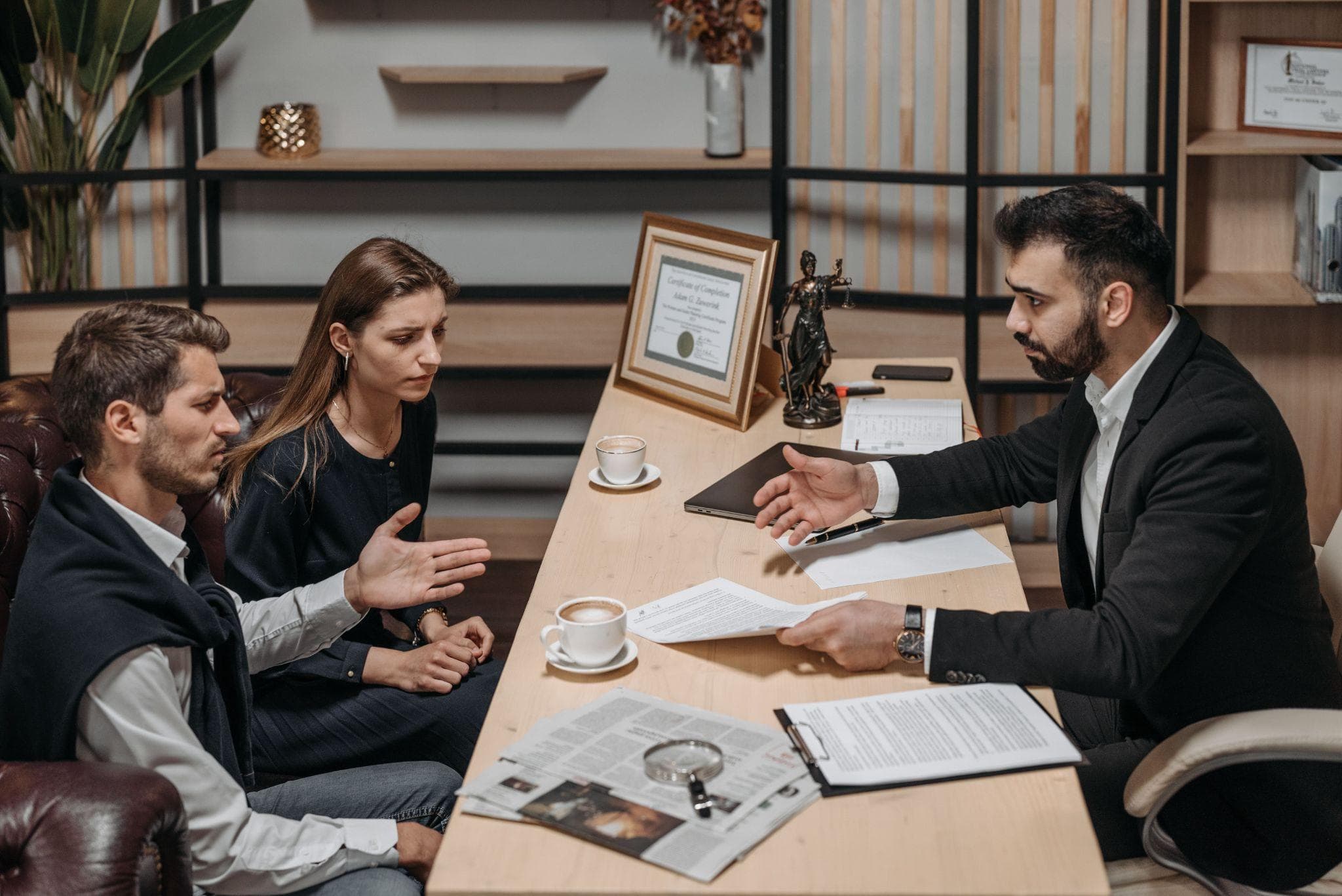 A solicitor explaining documents to a couple at a desk during an initial client meeting