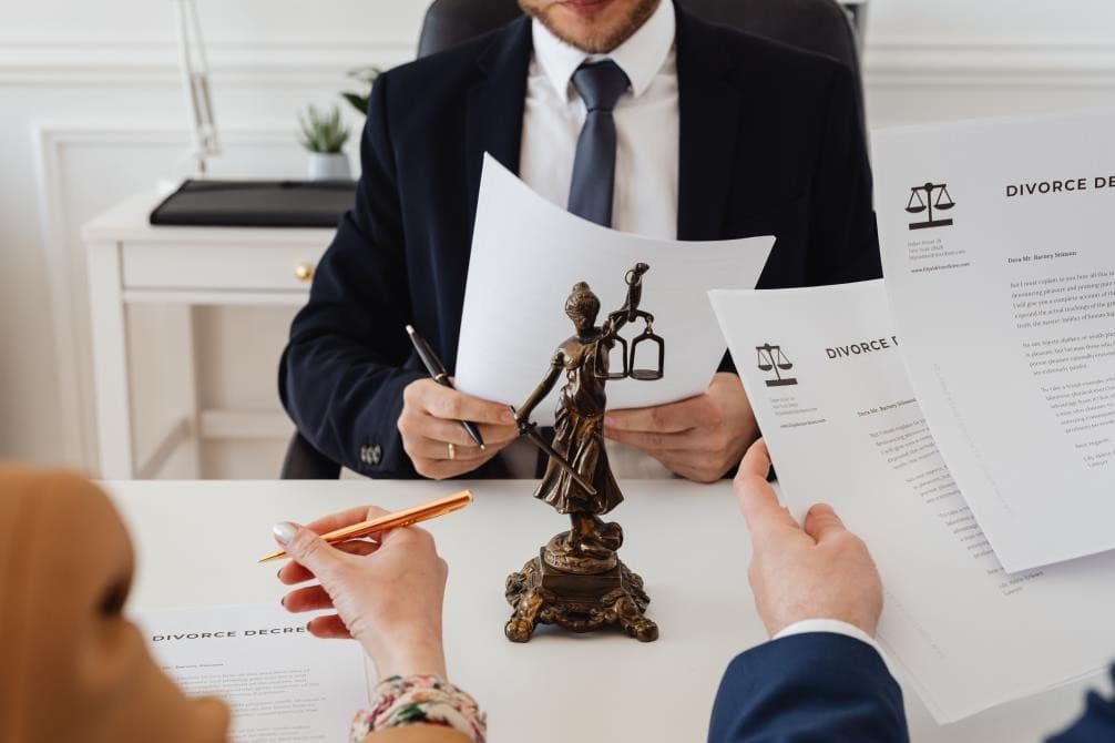 A solicitor and clients reviewing divorce decree papers beside a statue of Lady Justice
