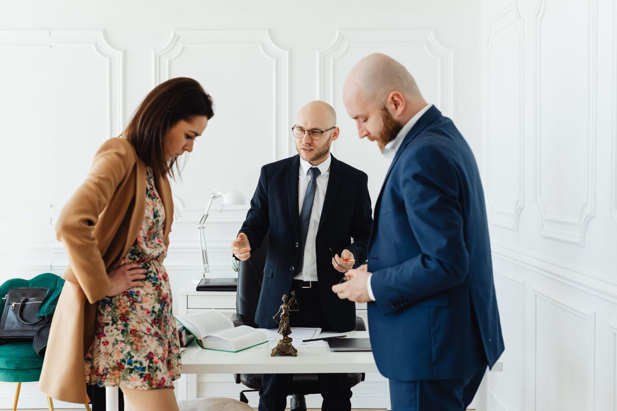 Three people standing around a desk discussing a personal injury case in a bright office