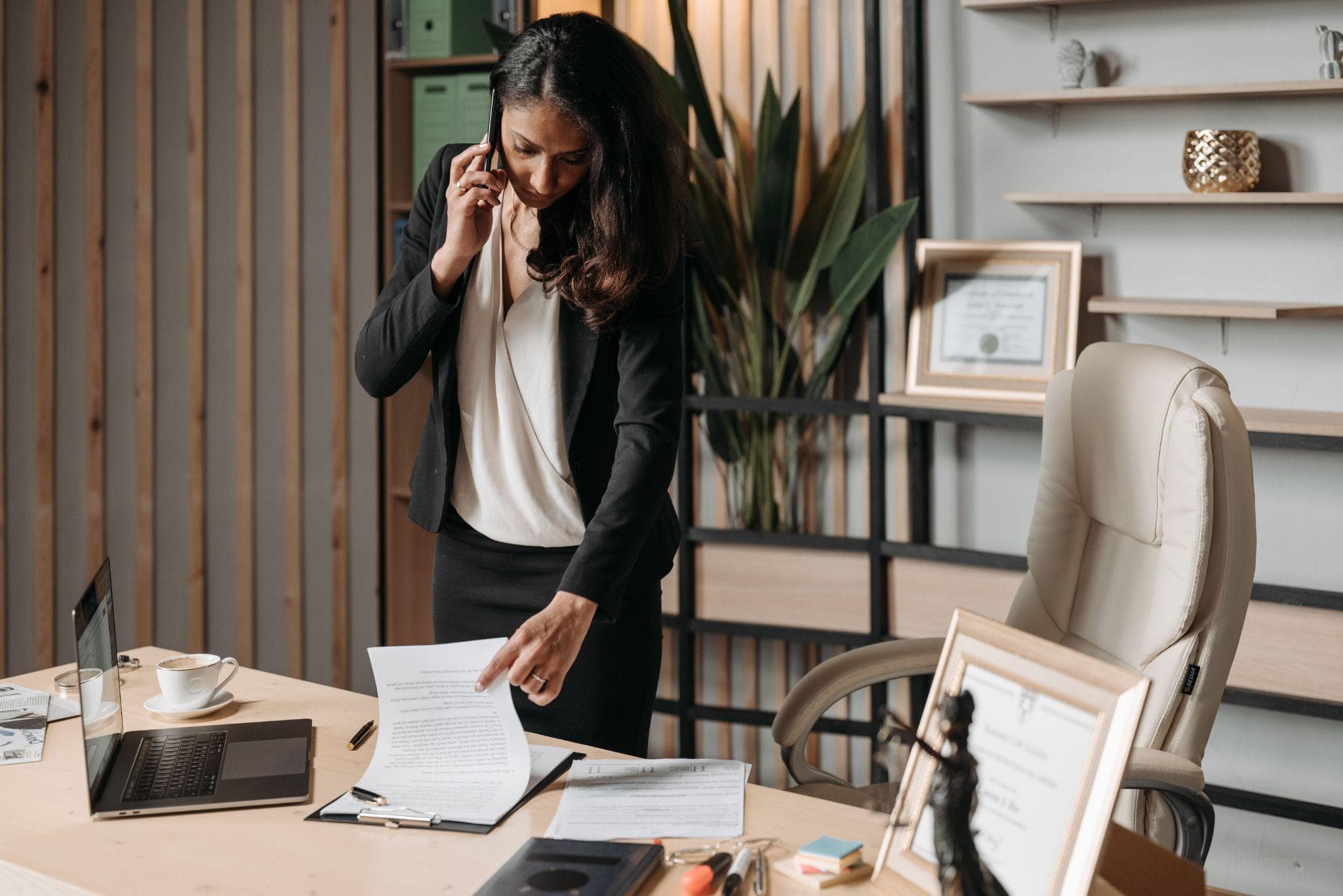 A solicitor on the phone reviewing a claim document at her desk